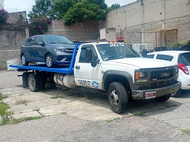 Grúa plataforma de Grúas Delta con un auto compacto cargado sobre la cama