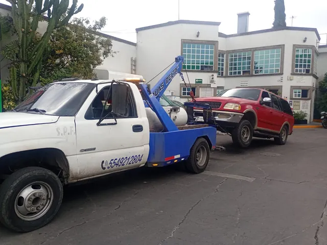 Grúa de arrastre levantando una camioneta SUV roja por el frente